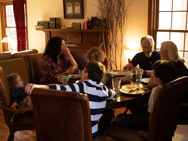 woman enjoys dinner with the host family who cared for her twin boys while she was in crisis