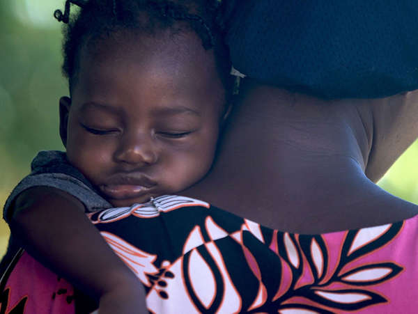 A Ghanaian mother holds her sleeping son as they walk home.