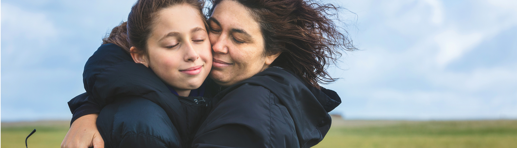 A mom embraces her teen daughter  