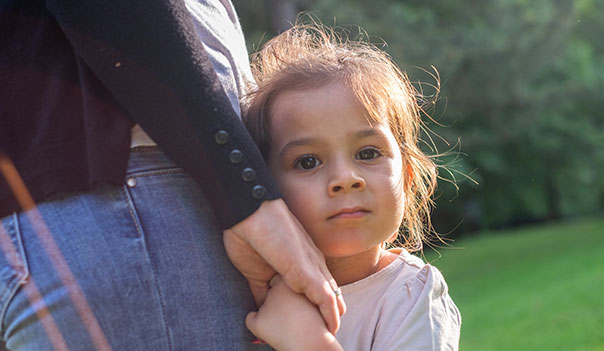 young adopted girl hugs closely to her mother's side