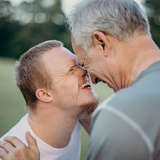 adoptive father and his son with special needs touch foreheads and smile