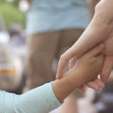 adoptive mother holds the hand of her young child