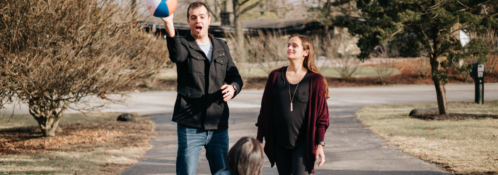 White male foster parent tosses beach ball to migrant girl