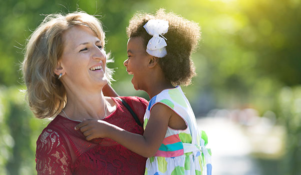 adoptive mother holds her multiracial daughter in their backyard
