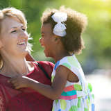 adoptive mother holds her multiracial daughter in their backyard