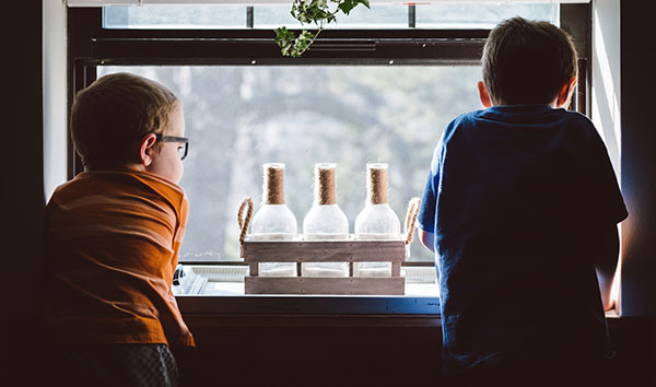 two young boys in foster care look out the window of their foster parents' home