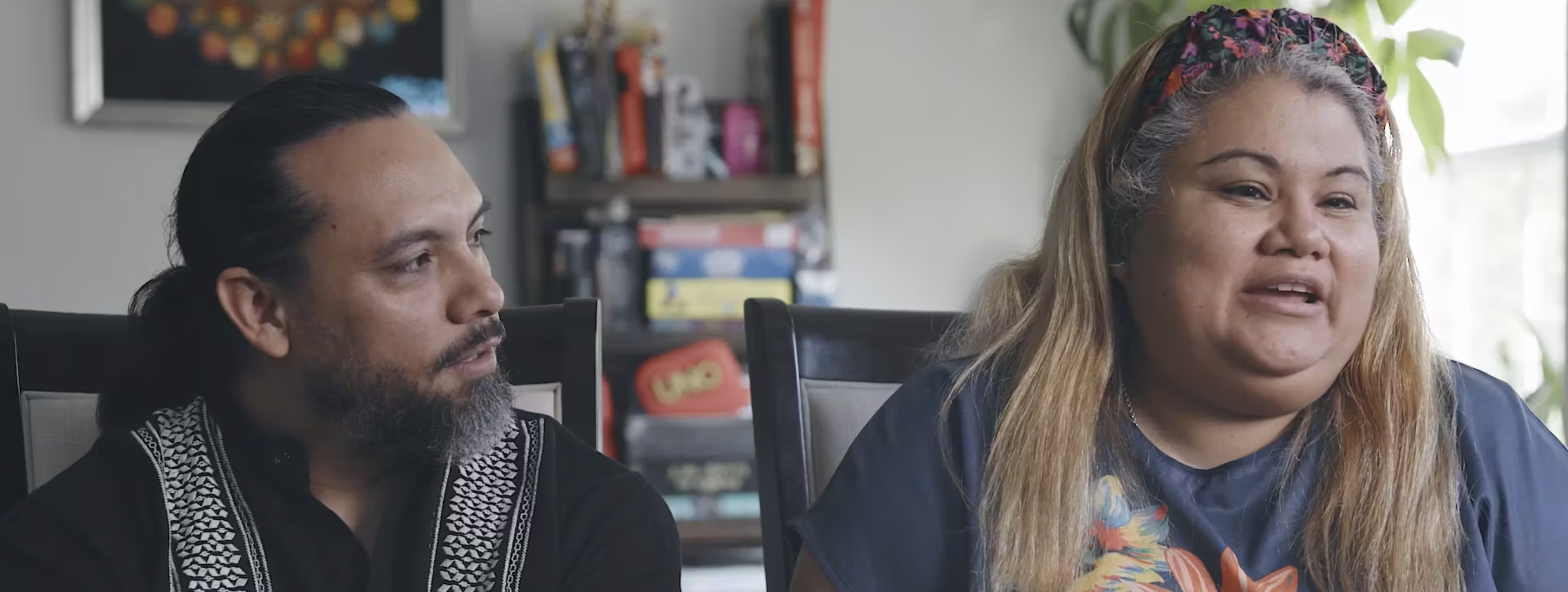 Diverse refugee foster parents sit in living room