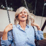 elderly white woman laughs while swinging