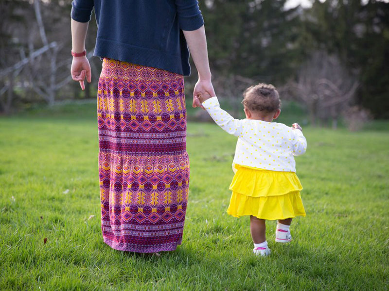birth mother holds her daughter's hand during an open adoption visit