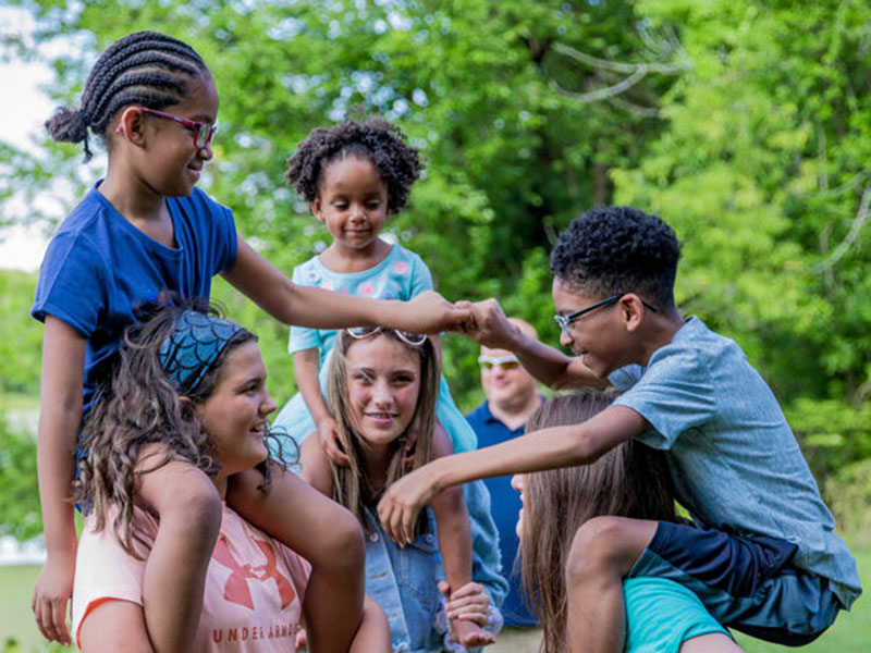 diverse foster kids climb on shoulders of older kids