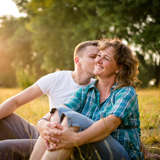 adopted son kisses his birth mother on the cheek in a sunny field