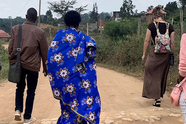 A group of adult refugees travels along a dirt road.