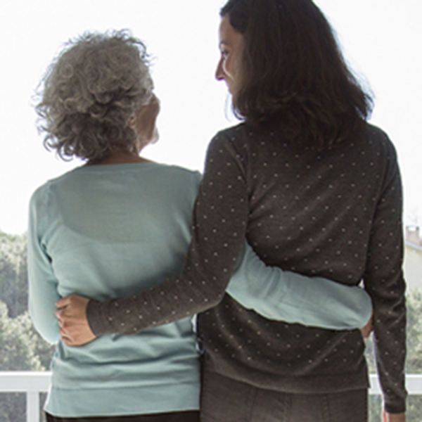 elderly mother and adult daughter embrace