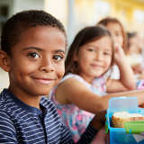 diverse group of schoolchildren eat their lunch