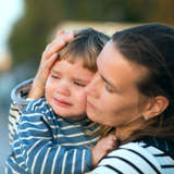 foster mother holds young boy who is crying