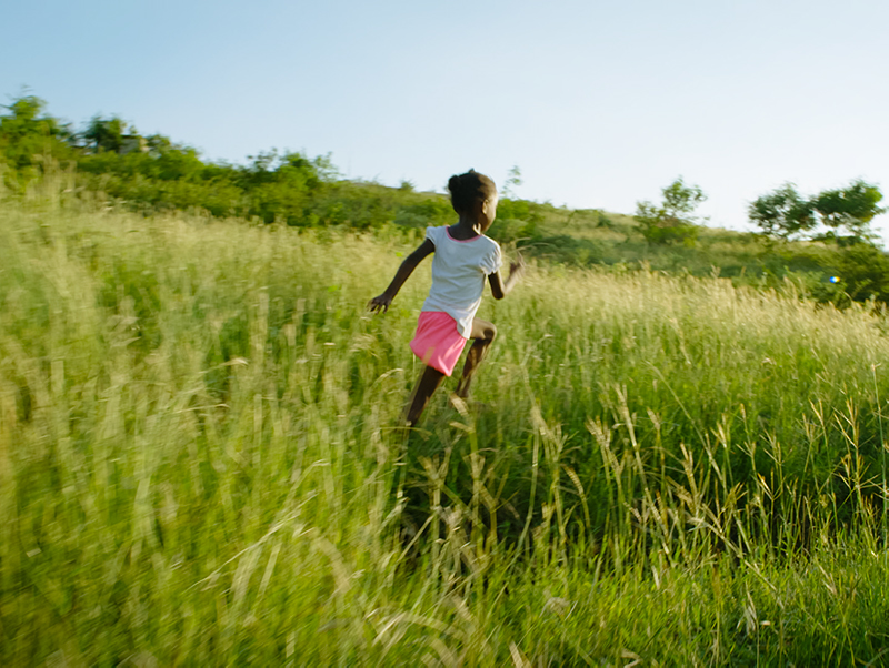 young haitian girl runs through a meadow as she tries to find her way home