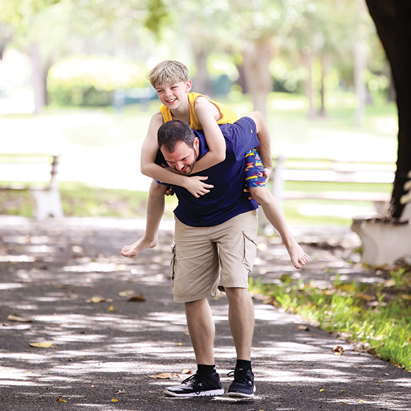 young white male climbs on his birth father's back outside