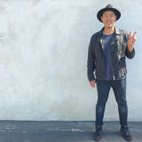 young asian adult adoptee holds up the peace sign in front of a concrete wall