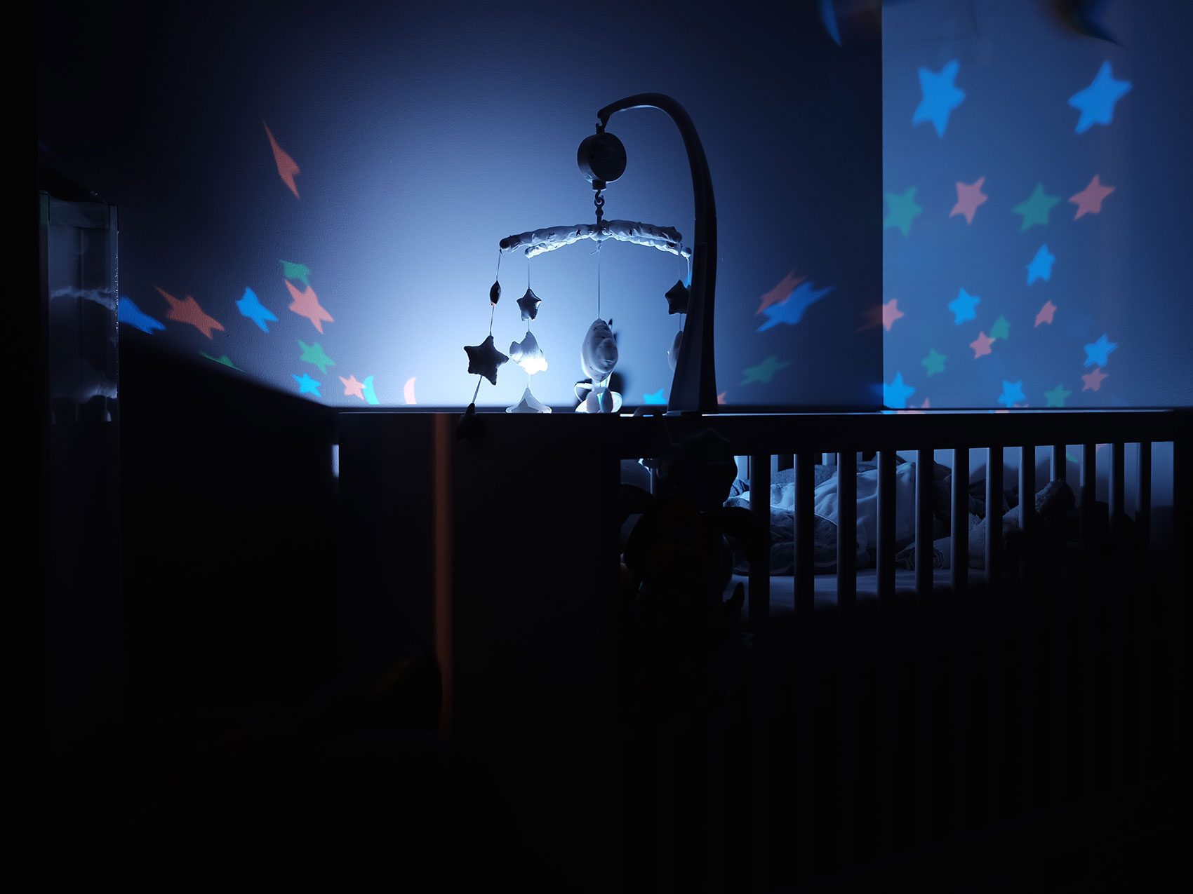 a crib is lit up showing a mobile in the nursery