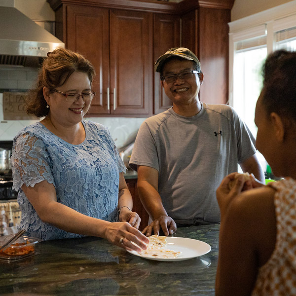 Vietnamese parents laugh with kids in kitchen.