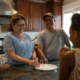 Vietnamese parents laugh with kids in kitchen.